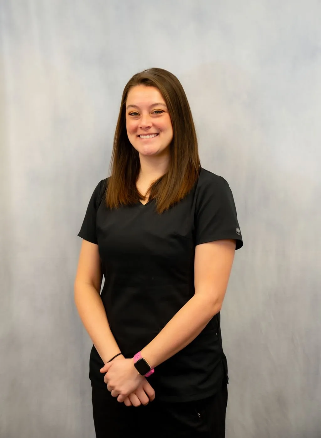 Studio portrait of Dr. Melany Leek smiling in dark scrubs against a grey backdrop