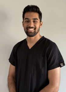 Headshot of Dr. Mrunal Shah smiling in dark V-neck scrubs against a light grey background
