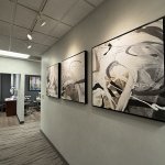 Clinic hallway lined with framed abstract artwork leading toward open treatment rooms