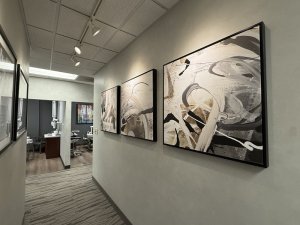 Clinic hallway lined with framed abstract artwork leading toward open treatment rooms