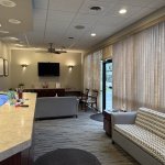 Reception and waiting area showing the front check-in counter, seating sofa, television, and window blinds